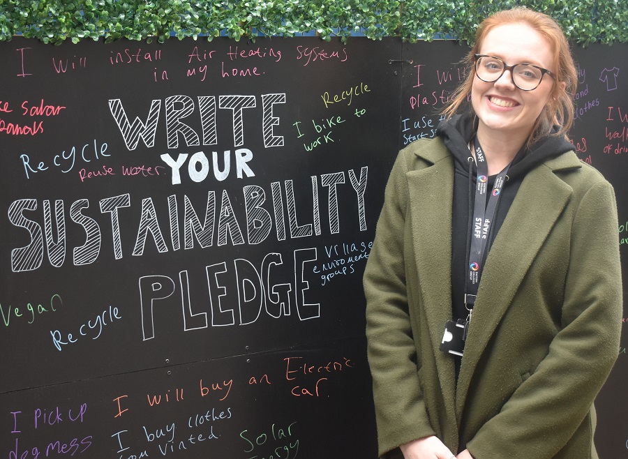 Jazz Godfrey from the sustainability team writes something down on the pledge wall at the SOS green event in Bury