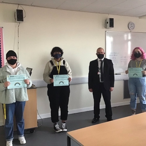 Photo of four people standing in a line 3 holding certificates