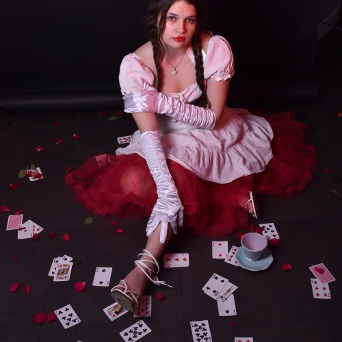 Person sitting with a red and white dress with playing cards spread around her