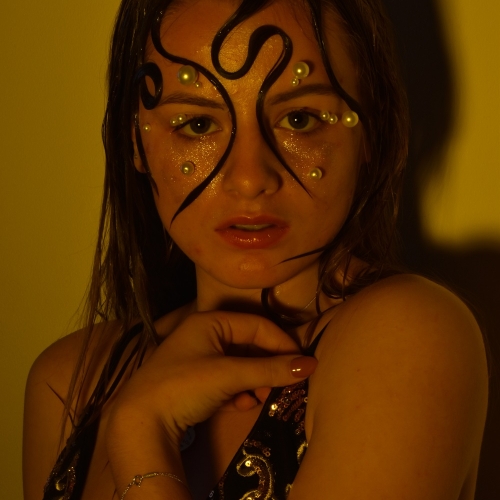 close up with a person posing with wet hair and pearls on her face