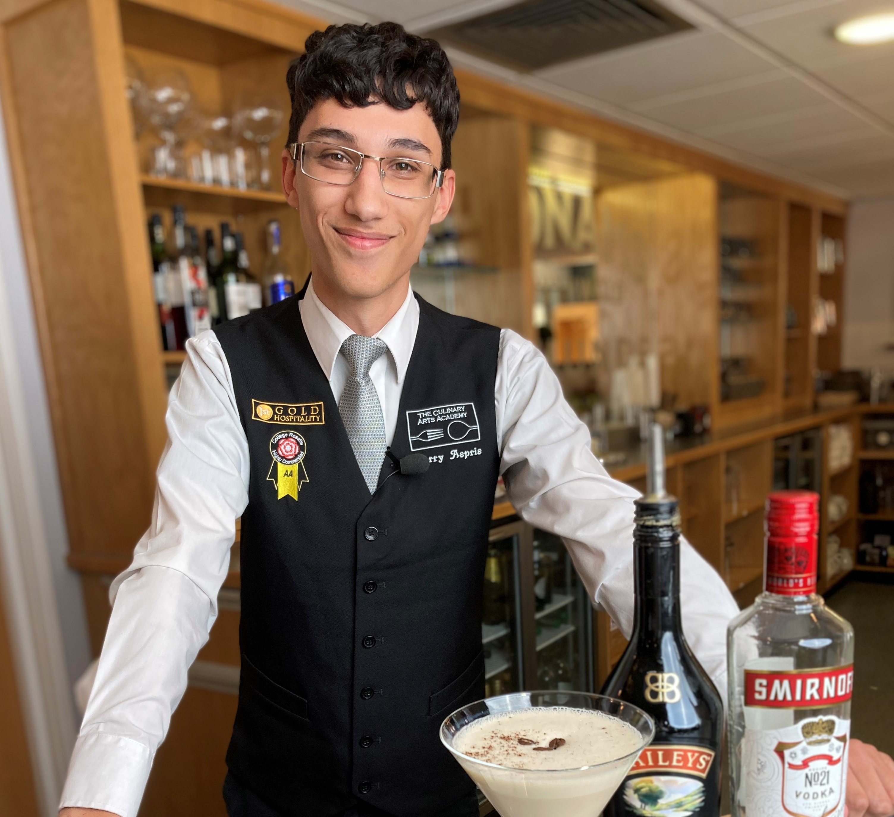 Culinary Arts Academy student barman smiling at camera with cocktails and mocktails in foreground
