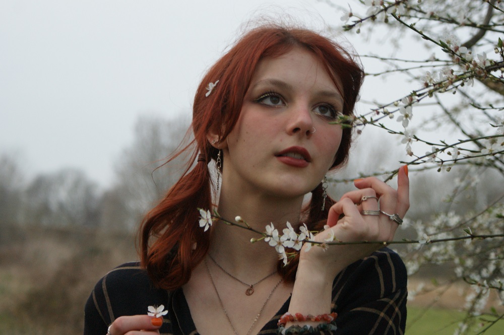 Jesse Withers Music Artist - girl with red hair standing next to tree with white blossom looking at tree