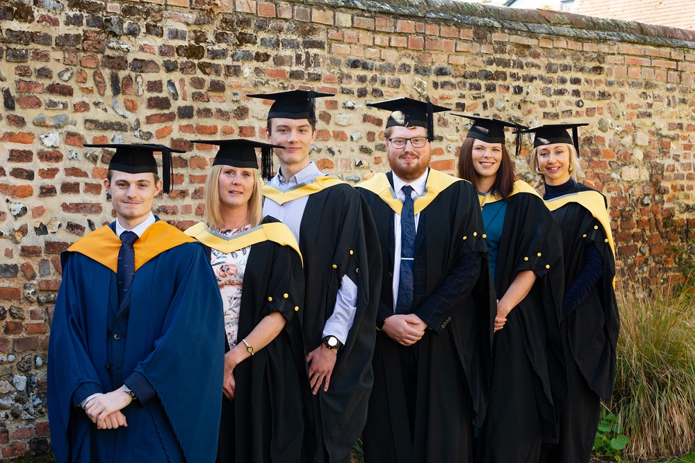 Pictures are six winners of special awards at the University Studies at West Suffolk College 2022 graduation in a garden facing the camera and smiling.