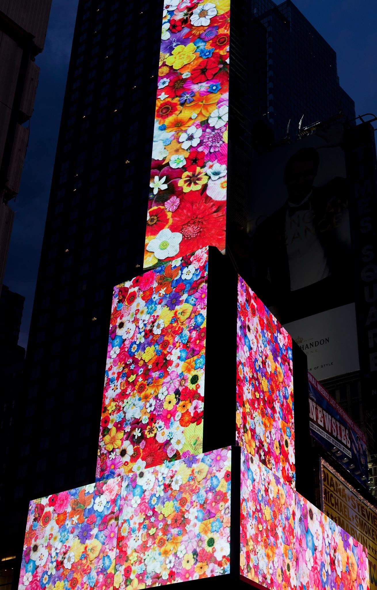 Photo of a high rise in time square with flowers on the screens