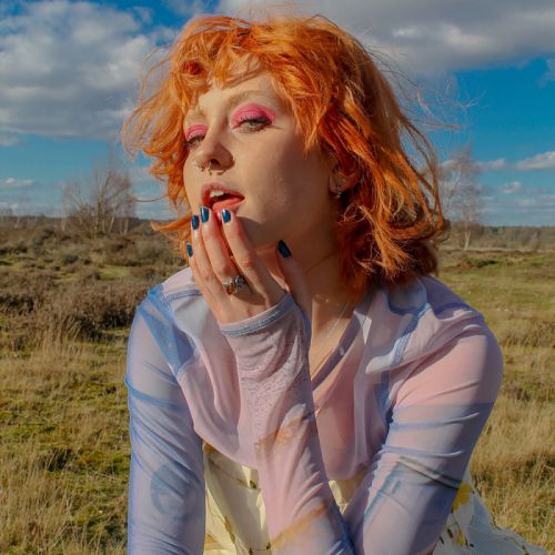 person posing in a field with ginger hair and makeup