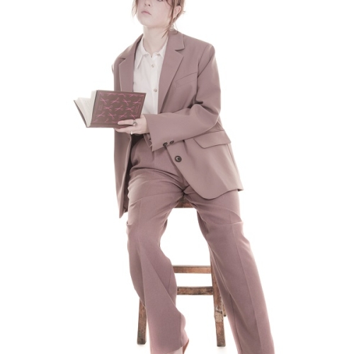 person sitting on a chair looking into the air whilst holding an open book