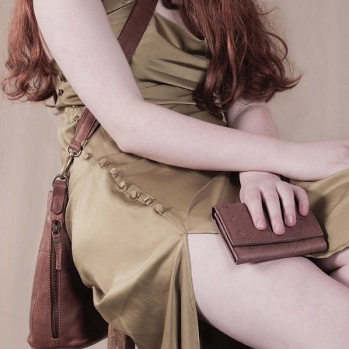 person sitting on a stool in a greenish dress, holding a purse