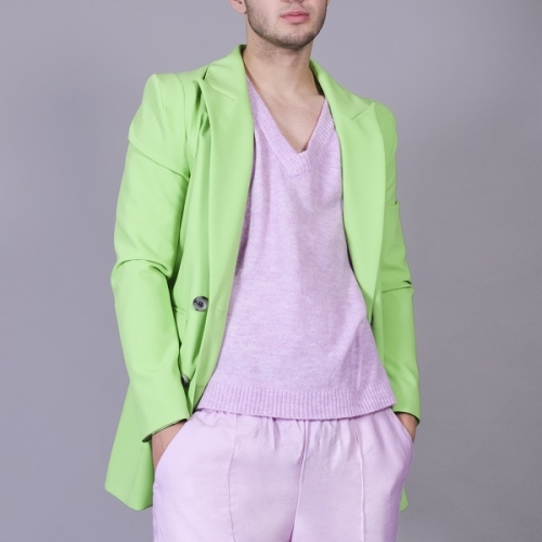 person posing and looking at the camera with a bright green jacket and pink jumper and trousers