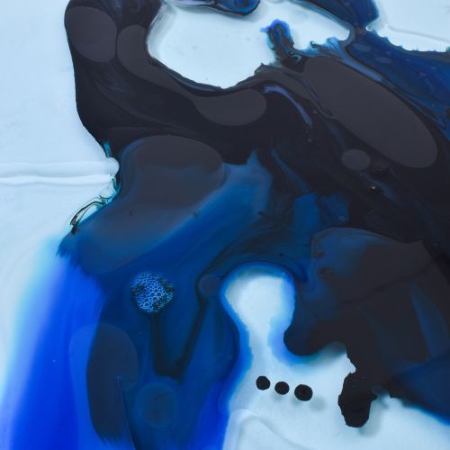 Photo of a spill of paint with a mix of blue, black, grey