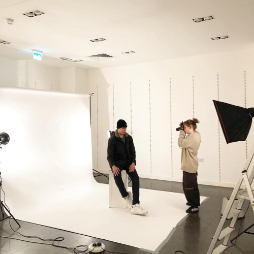 photographer taking an image of a person in a all black with white trainers