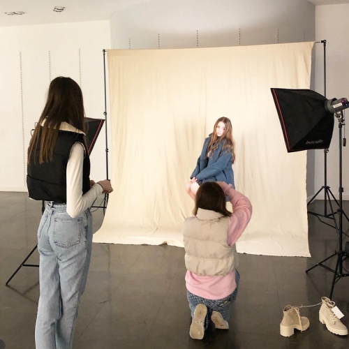 photographer taking an image of a person in a blue jacket posing