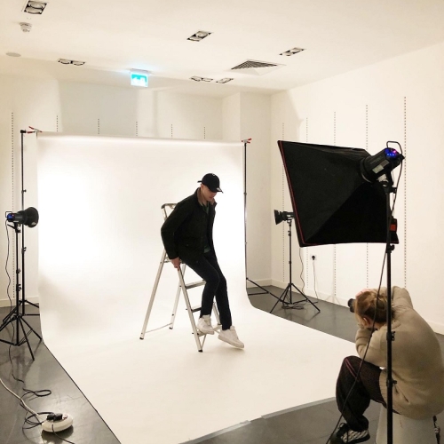 photographer taking an image of a person in all black leaning against a stepladder