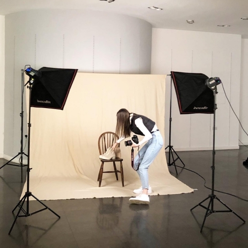 photographer setting up a set, with a wooden chair and shoes on the chair