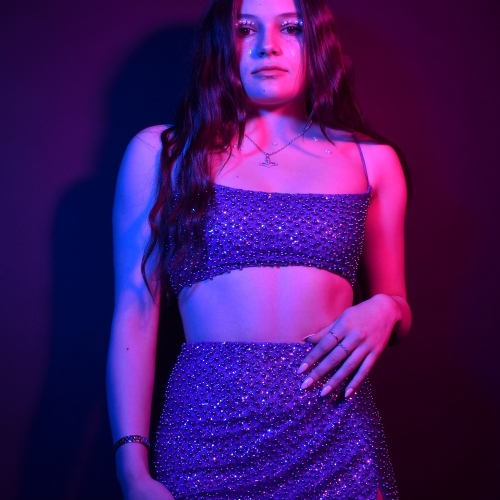 person posing and looking down at the camera in a dress covered in sequins