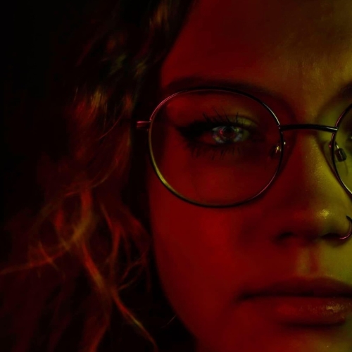 Close up photo of a person with glasses with a red glow