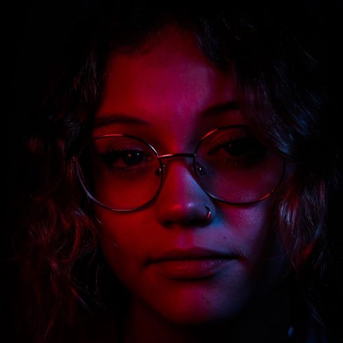 Close up photo of a person with glasses with a red glow