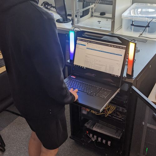 Photo of a person using a laptop on a server rack