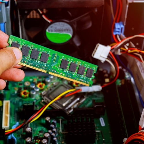 Close up inside a server with a hand holding a stick of ram