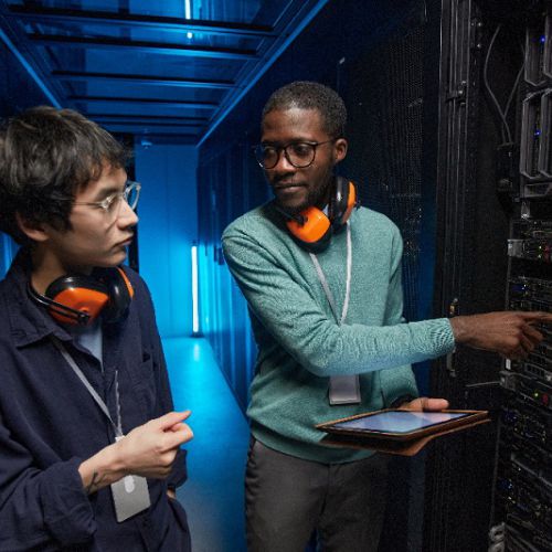 two people in a server room looking and pointing at a server rack